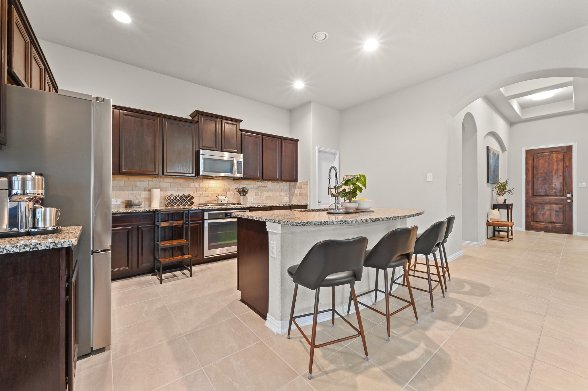 546 Hot Spring Valley Buda, TX 78610 - Photo 10 of 27 Kitchen with a center island with sink, light stone countertops, a breakfast bar, stainless steel appliances, and arched walkways