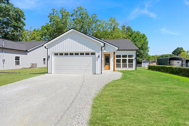 a view of a house next to a yard with big trees