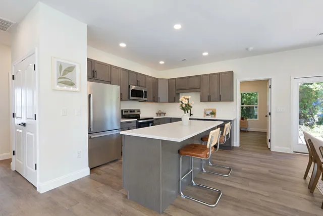 a kitchen with stainless steel appliances a refrigerator a stove a sink a dining table and chairs