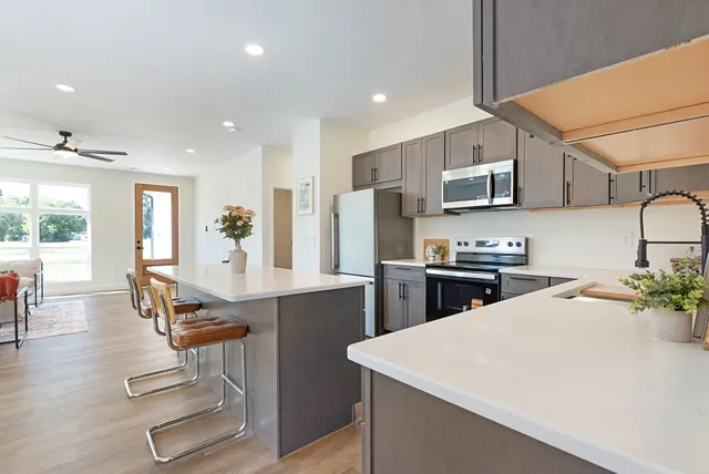 a kitchen with stainless steel appliances kitchen island granite countertop a sink a stove a refrigerator cabinets and a dining table