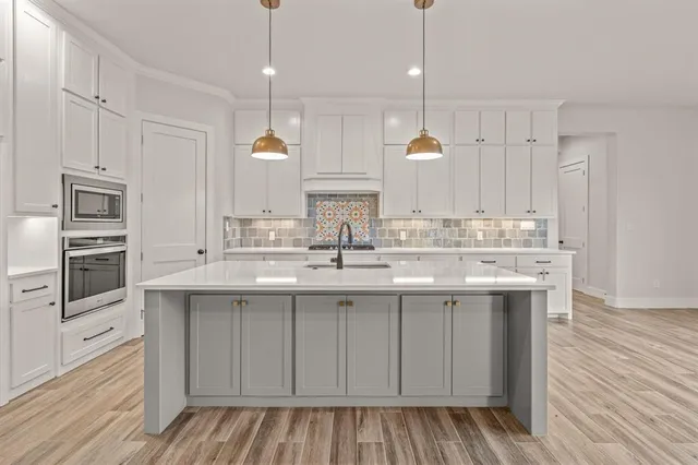 a kitchen with kitchen island granite countertop a sink cabinets and stainless steel appliances
