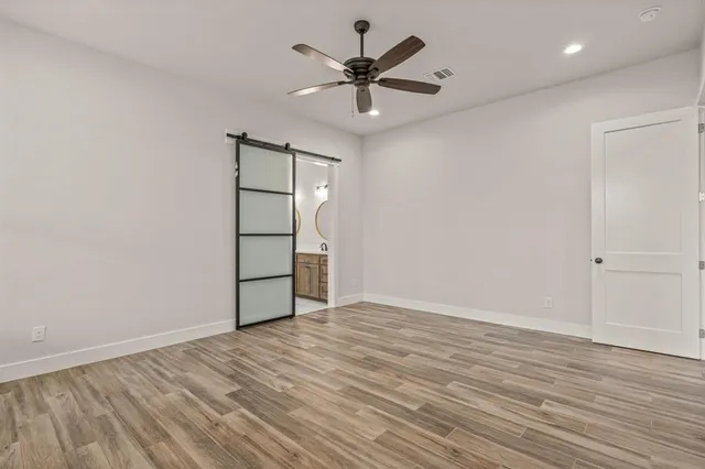 an empty room with wooden floor and ceiling fan