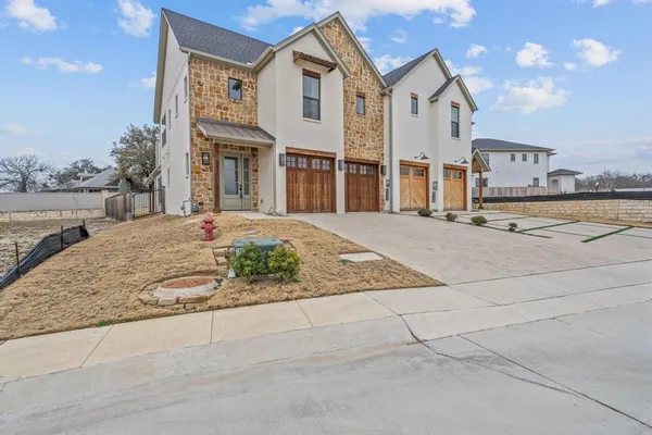 a view of a white house with large windows and palm trees