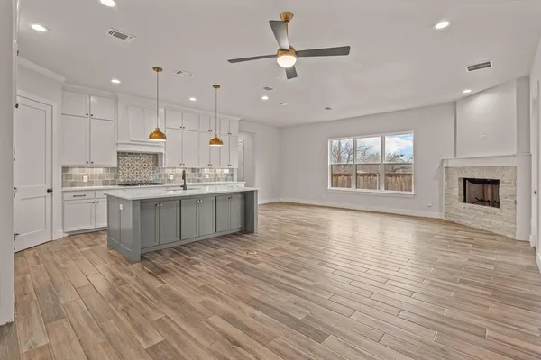 a large kitchen with stainless steel appliances granite countertop a stove top oven a sink with wooden floors