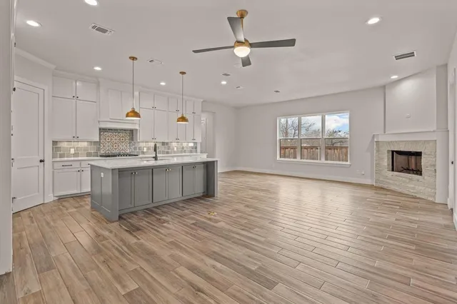 a large kitchen with stainless steel appliances granite countertop a stove top oven a sink with wooden floors