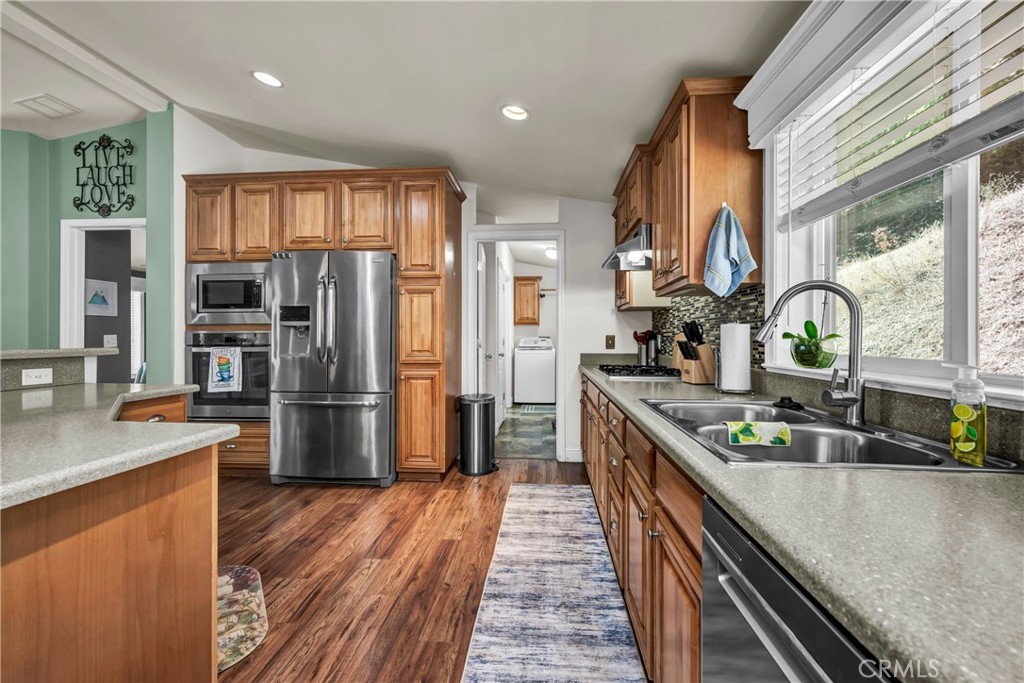 14986 Western Mine Road Middletown, CA 95461 - Photo 11 of 60 a kitchen with stainless steel appliances granite countertop a refrigerator a sink dishwasher a stove and a dining table with wooden floor