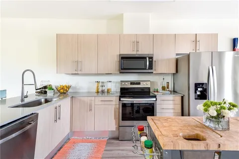 a kitchen with stainless steel appliances a stove a sink a refrigerator a stove a microwave and cabinets