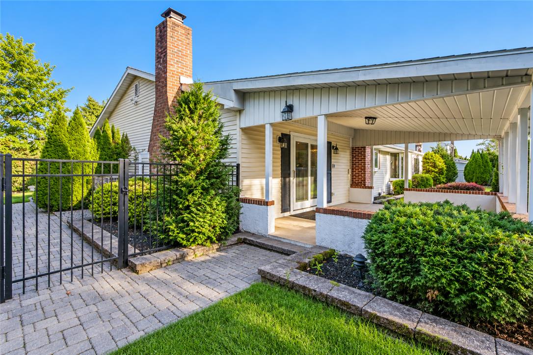 A classic brick chimney and covered patio highlight this welcoming exterior entrance.