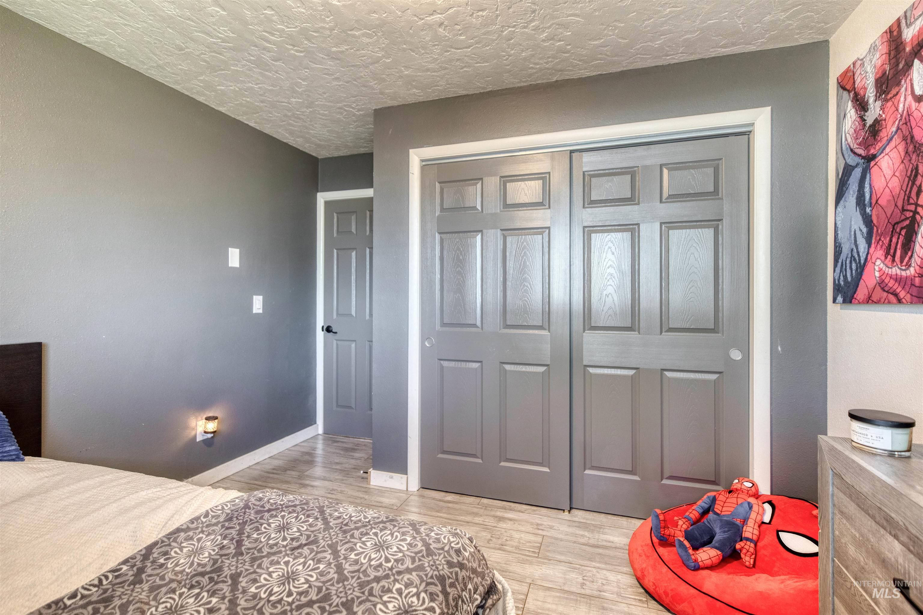 20803 Friends Road Greenleaf, ID 83626 - Photo 17 of 39 Bedroom featuring light wood-finish flooring, two-panel bifold closet doors, and a neutral wall color