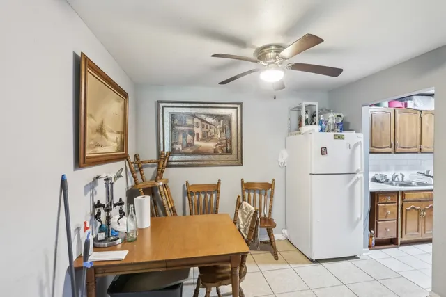 a white kitchen with a refrigerator a table and chairs