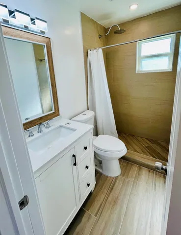 a bathroom with a sink a toilet a mirror and shower