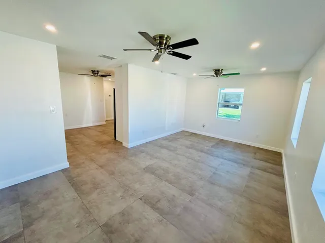 an empty room with a ceiling fan and window