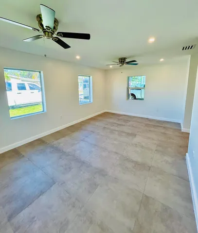 an empty room with windows and fan