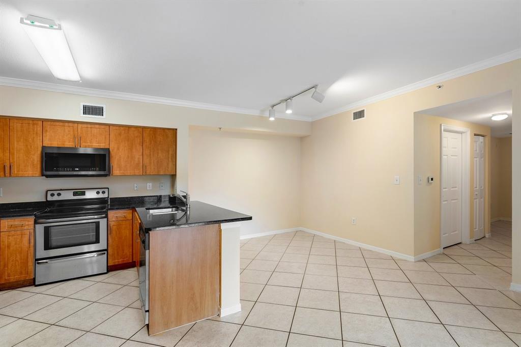 6492 Emerald Dunes Drive, Unit 208 West Palm Beach, FL 33411 - Photo 5 of 37 a kitchen with stainless steel appliances a stove a sink and a refrigerator