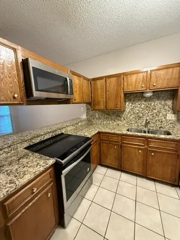 a kitchen with granite countertop a stove a sink and a microwave