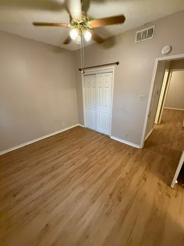 an empty room with wooden floor closet and fan