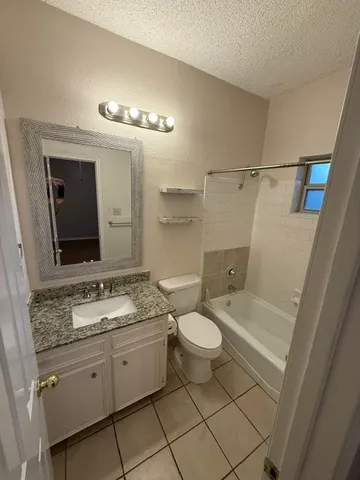 a bathroom with a granite countertop sink mirror vanity and toilet
