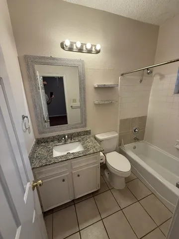a bathroom with a granite countertop sink mirror vanity and toilet