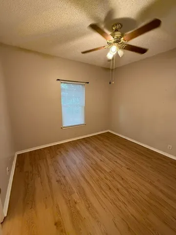 an empty room with wooden floor and fan