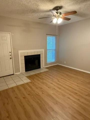 a view of an empty room with a fireplace and a chandelier fan