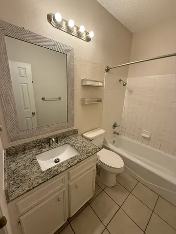 a bathroom with a granite countertop sink toilet a shower a mirror and a bathtub