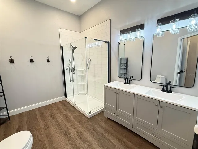 a bathroom with a double vanity sink a mirror and a shower
