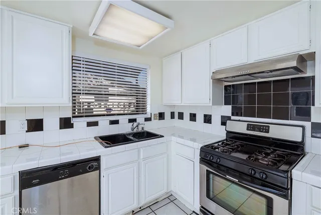 a kitchen with granite countertop a stove sink and cabinets