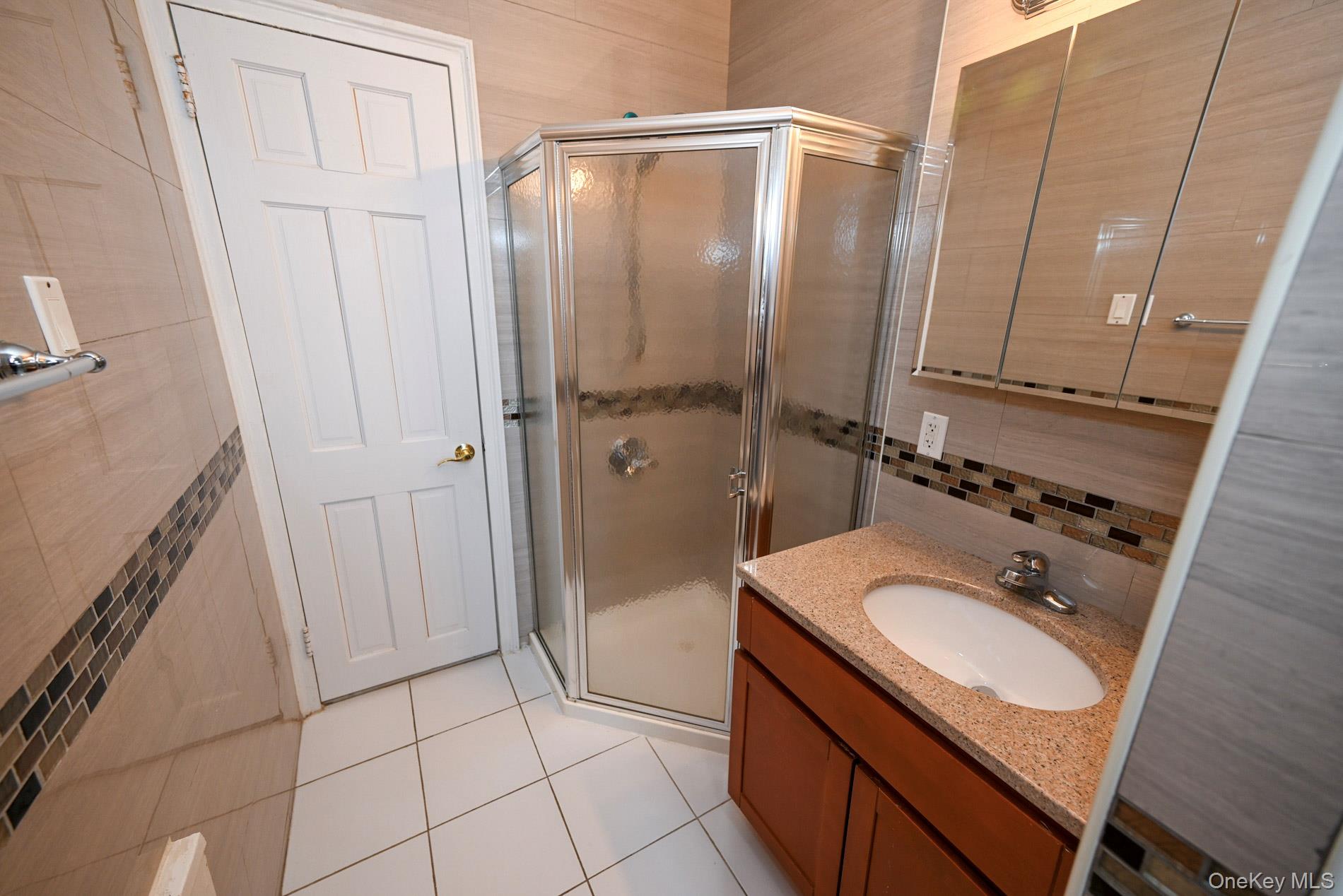 111-39 76th Road, Unit D7 Queens, NY 11375 - Photo 15 of 18 Bathroom with a stall shower, tasteful backsplash, tile patterned flooring, vanity, and tile walls