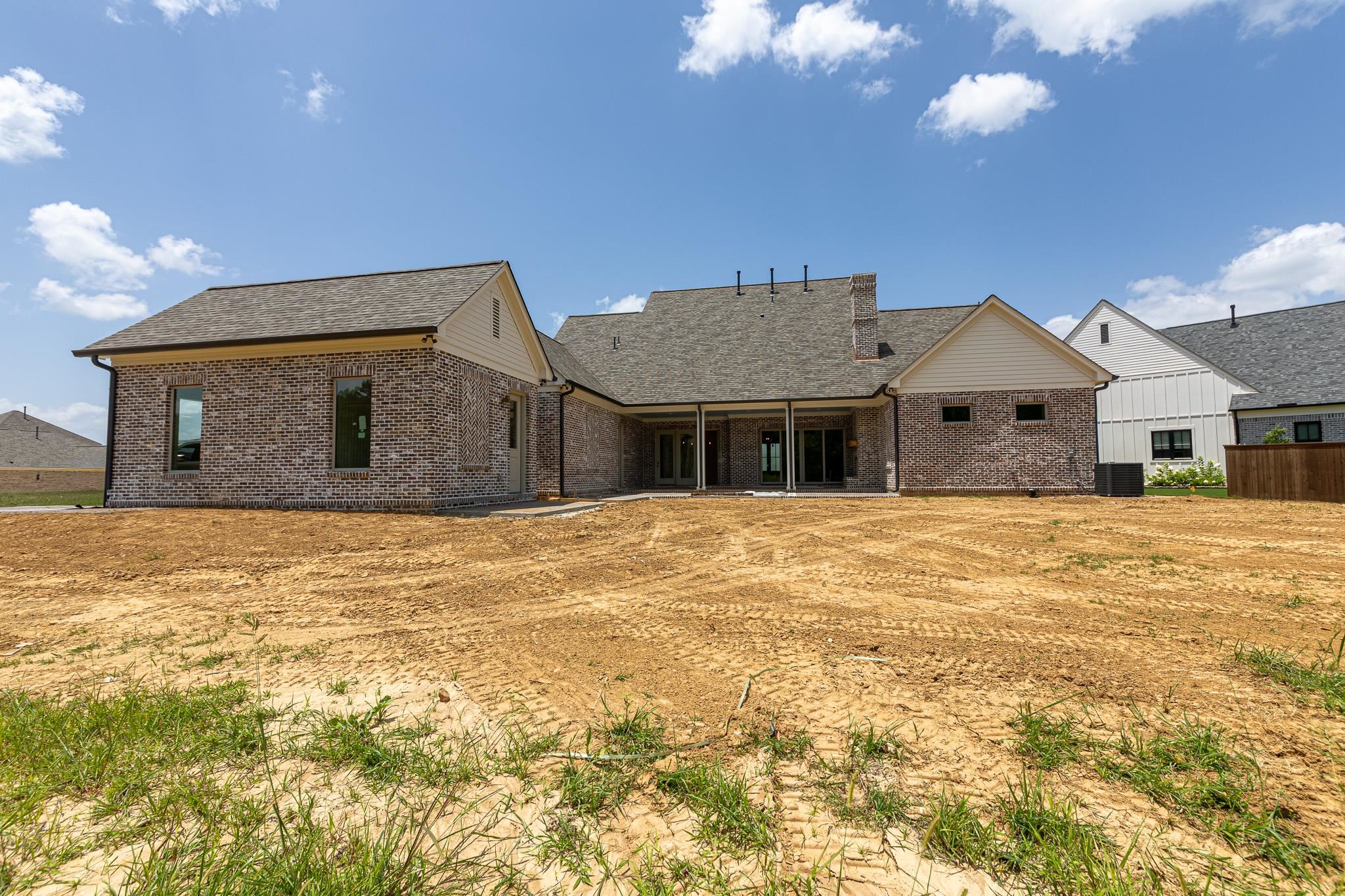 55 New Pond Road Piperton, TN 38017 - Photo 3 of 4 Newly constructed brick exterior featuring a covered patio, multiple windows, and dark roof shingles