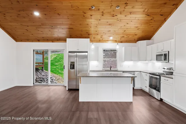 a kitchen with stainless steel appliances granite countertop a wooden floors a stove and a microwave