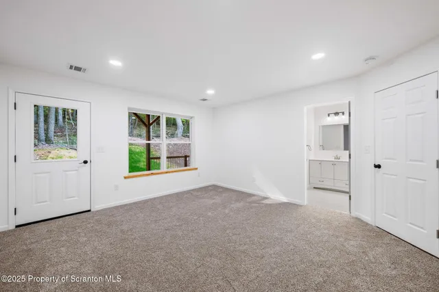 a view of an empty room with a window and a kitchen