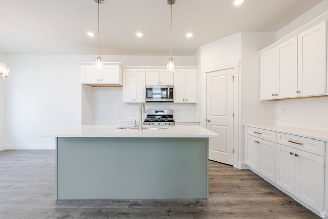 4769 Olive Avenue, Unit 411 Mapleton, UT 84664 - Photo 9 of 19 Dual tone kitchen with a center island with sink, dual tone cabinets, pendant lighting, stainless steel appliances, and dark wood-style flooring