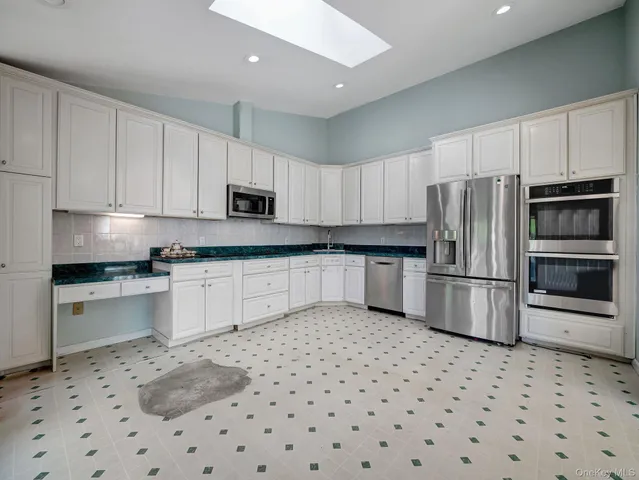 a spacious bedroom with a bed a dresser and wooden floor