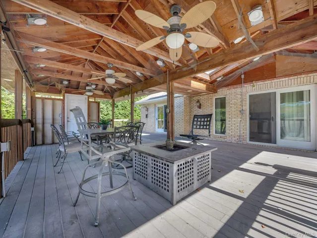 a view of a patio with table and chairs a barbeque with wooden floor and fence