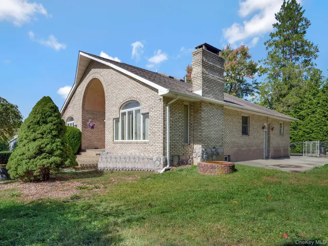 a backyard of a house with table and chairs plants and large tree
