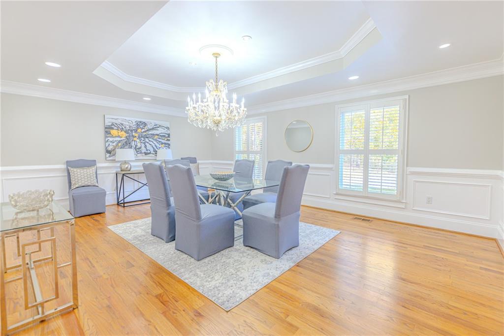 7680 Jett Ferry Road Atlanta, GA 30350 - Photo 11 of 74 a dining room with wooden floor a chandelier a glass table and chairs