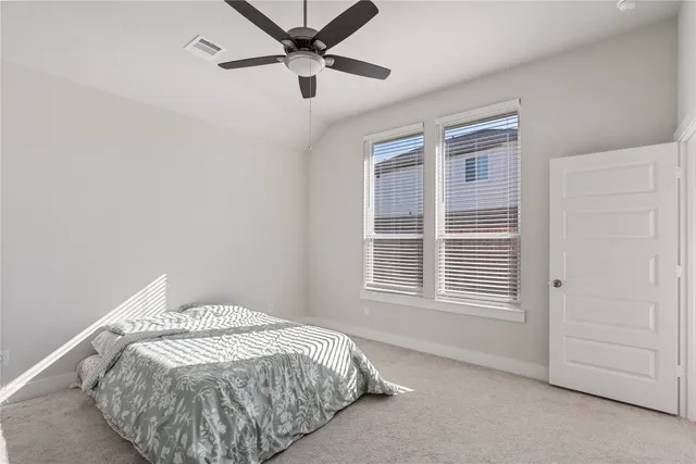 a bed sitting in a bedroom next to a window and a chandelier