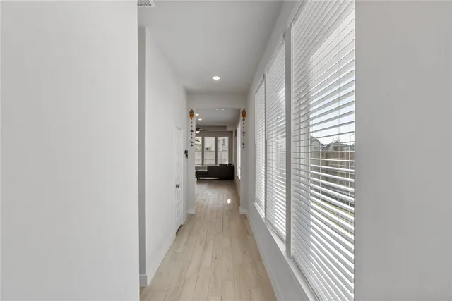 a view of a hallway with wooden floor and a bathroom