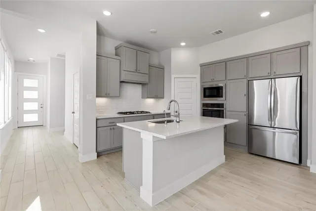 a kitchen with stainless steel appliances a refrigerator sink and cabinets