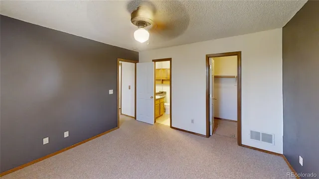 an empty room with a bathroom and chandelier fan