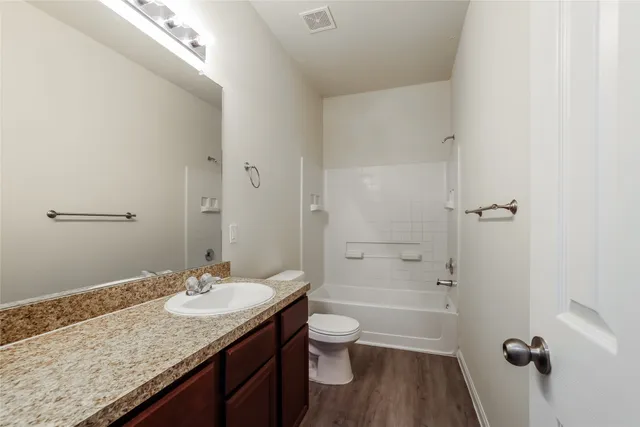 a bathroom with a granite countertop sink toilet a mirror and shower