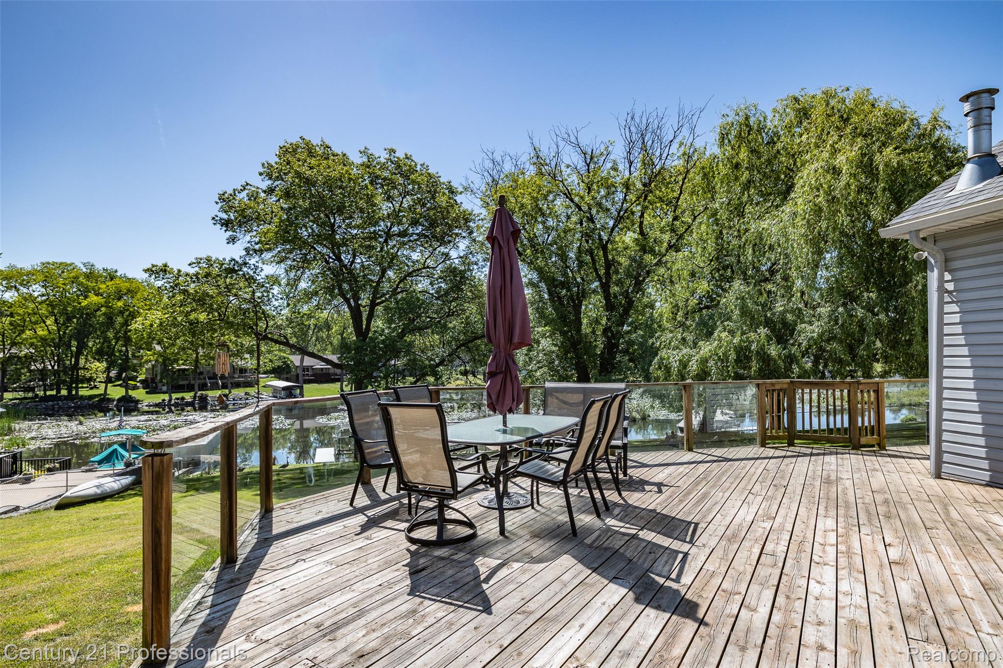 3251 Mann Road Clarkston, MI 48346 - Photo 3 of 40 Expansive wood deck with glass panel railing, offering open-air entertaining space