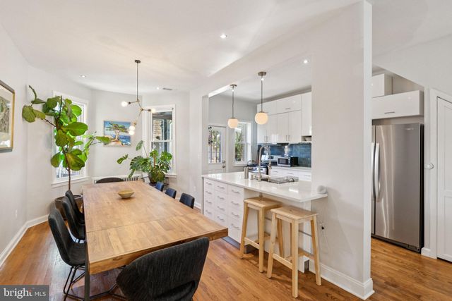 a kitchen with stainless steel appliances kitchen island granite countertop a refrigerator a stove and white cabinets with wooden floors