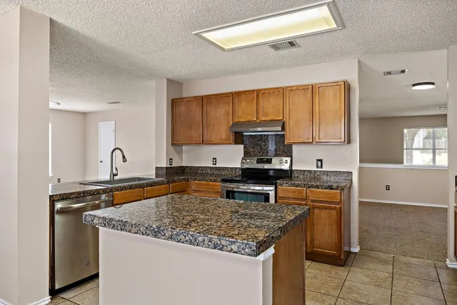 a kitchen with stainless steel appliances granite countertop a stove top oven a sink dishwasher a refrigerator and cabinets with wooden floor