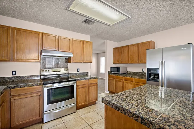 a kitchen with stainless steel appliances granite countertop a stove a sink dishwasher and a refrigerator