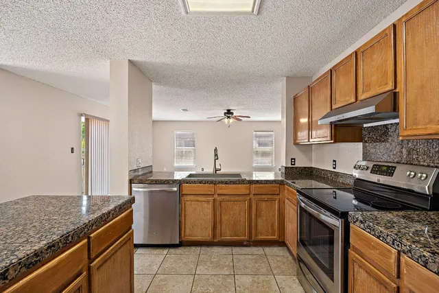 a kitchen with stainless steel appliances granite countertop a stove a sink dishwasher and cabinets with wooden floor