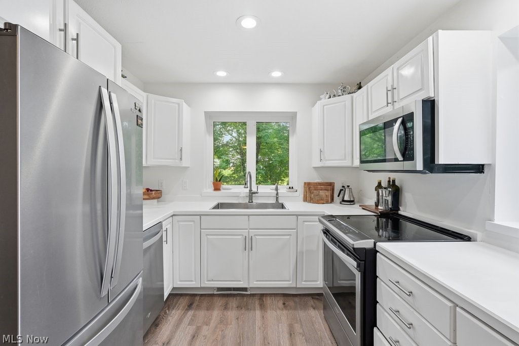 2323 Call Road Stow, OH 44224 - Photo 14 of 42 Kitchen featuring white shaker cabinetry, stainless steel appliances, light-toned countertops, wood-finish flooring, and recessed lighting