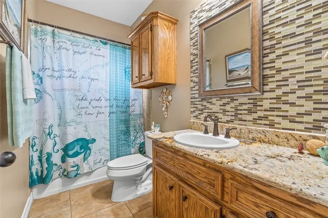 a bathroom with a granite countertop bathtub sink vanity mirror and toilet