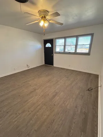 an empty room with chandelier fan and windows