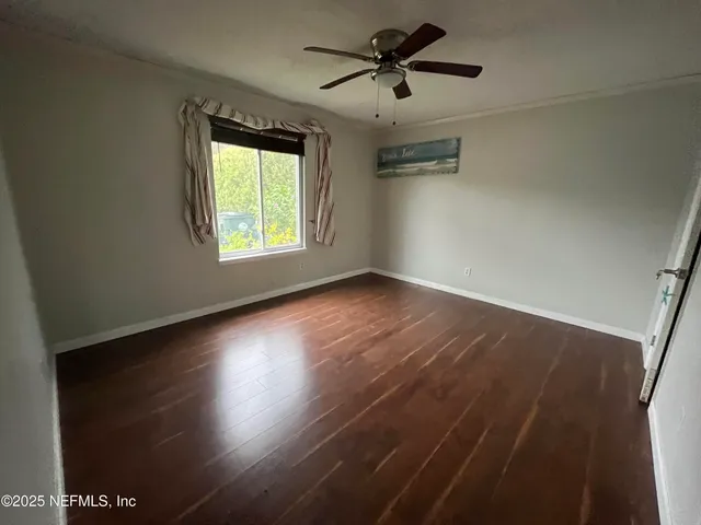 a view of empty room with wooden floor and fan